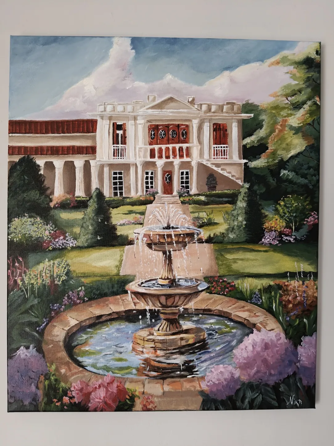 A house behind a stone fountain and flowering beds